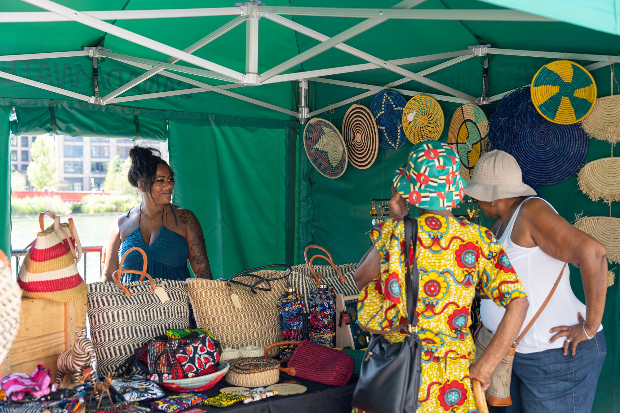 A trader and customers at a woven basket stall at the Craft & Flea market, Canada Water.