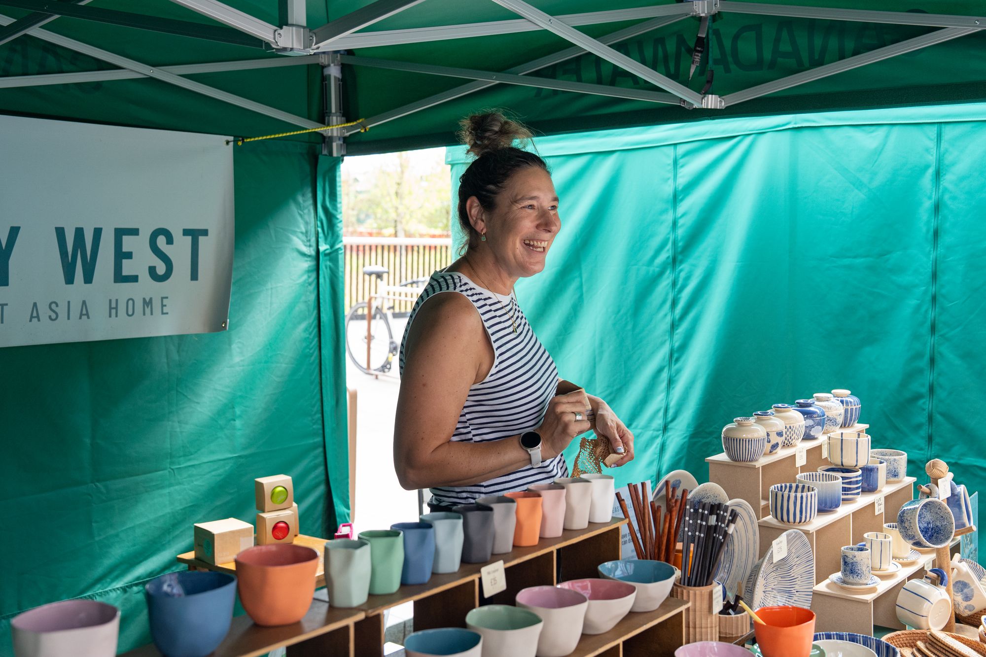 A ceramics trader serving a customer at the Craft & Flea market on the dockside at Canada Water.
