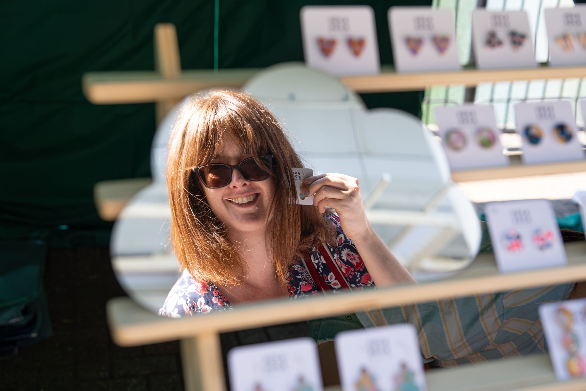 A shopper trying on earrings in a stall mirror at the Craft & Flea market, Canada Water.