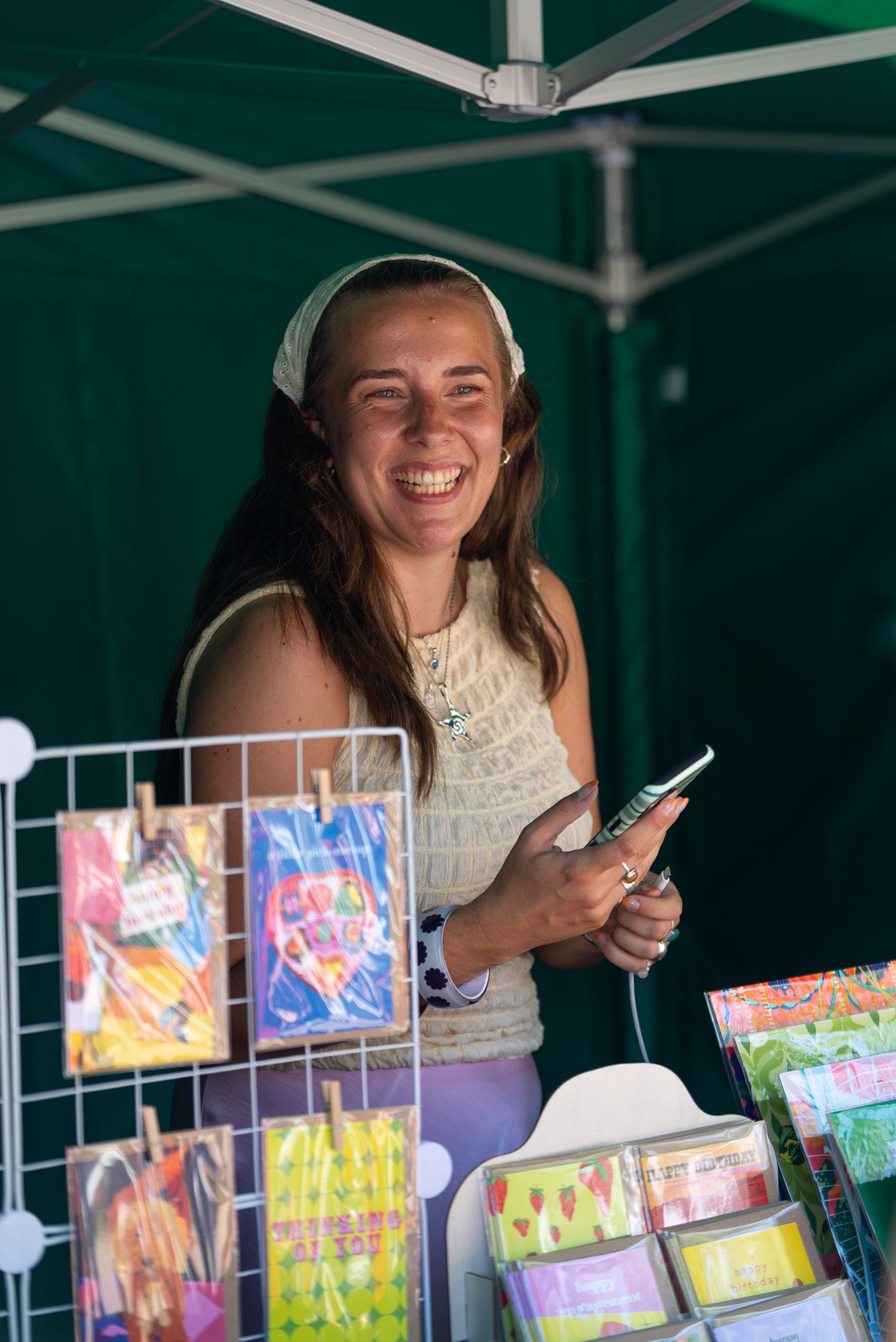 An illustrator smiling at her print stall at the Craft & Flea market, Canada Water.