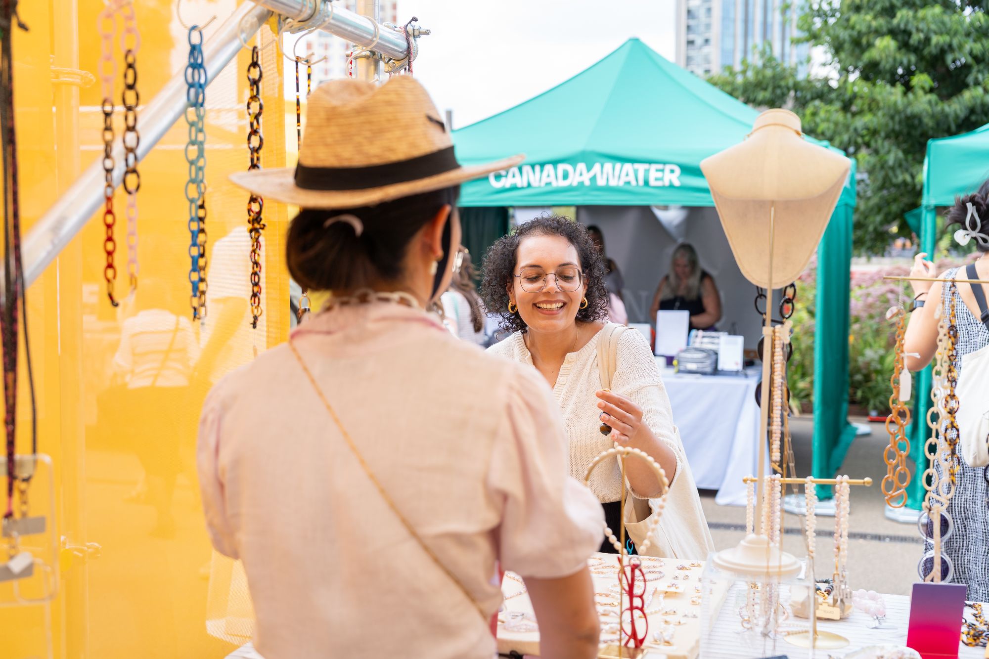 A jewellery maker laughing with a customer at her Craft & Flea stall, Canada Water, London SE16.