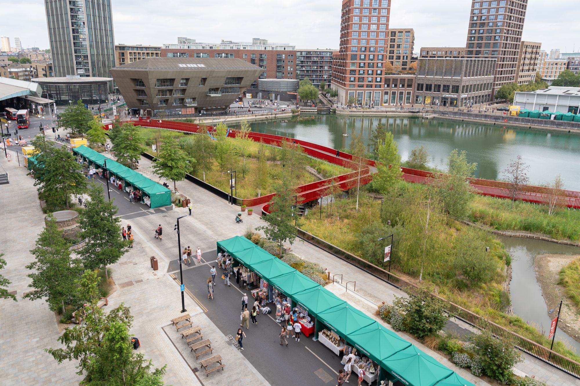 The Craft & Flea stalls lining the dockside at Canada Water, seen from above among the planting.