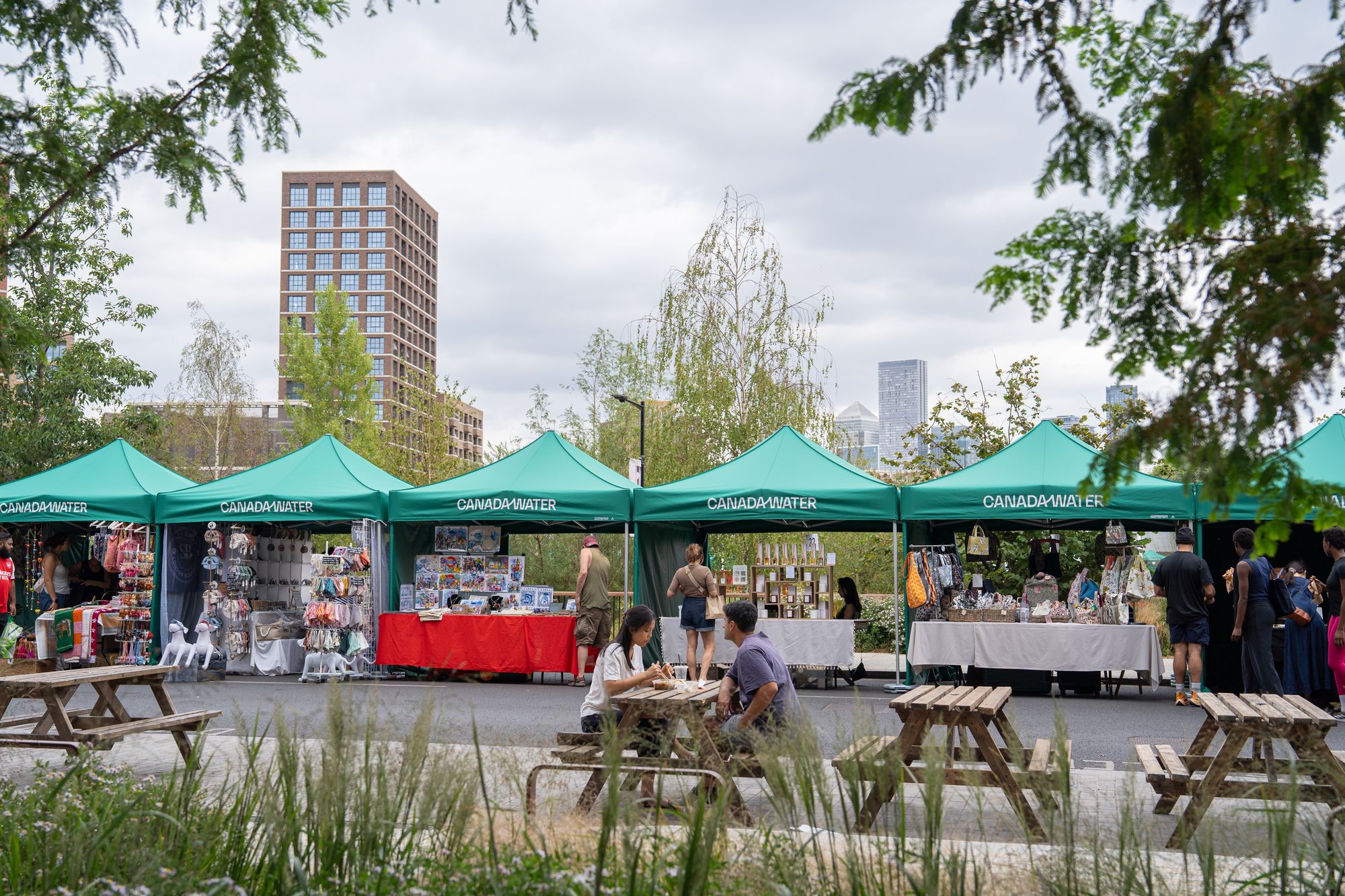 The Craft & Flea market seen through the planting around Canada Dock — the green setting of Canada Water.