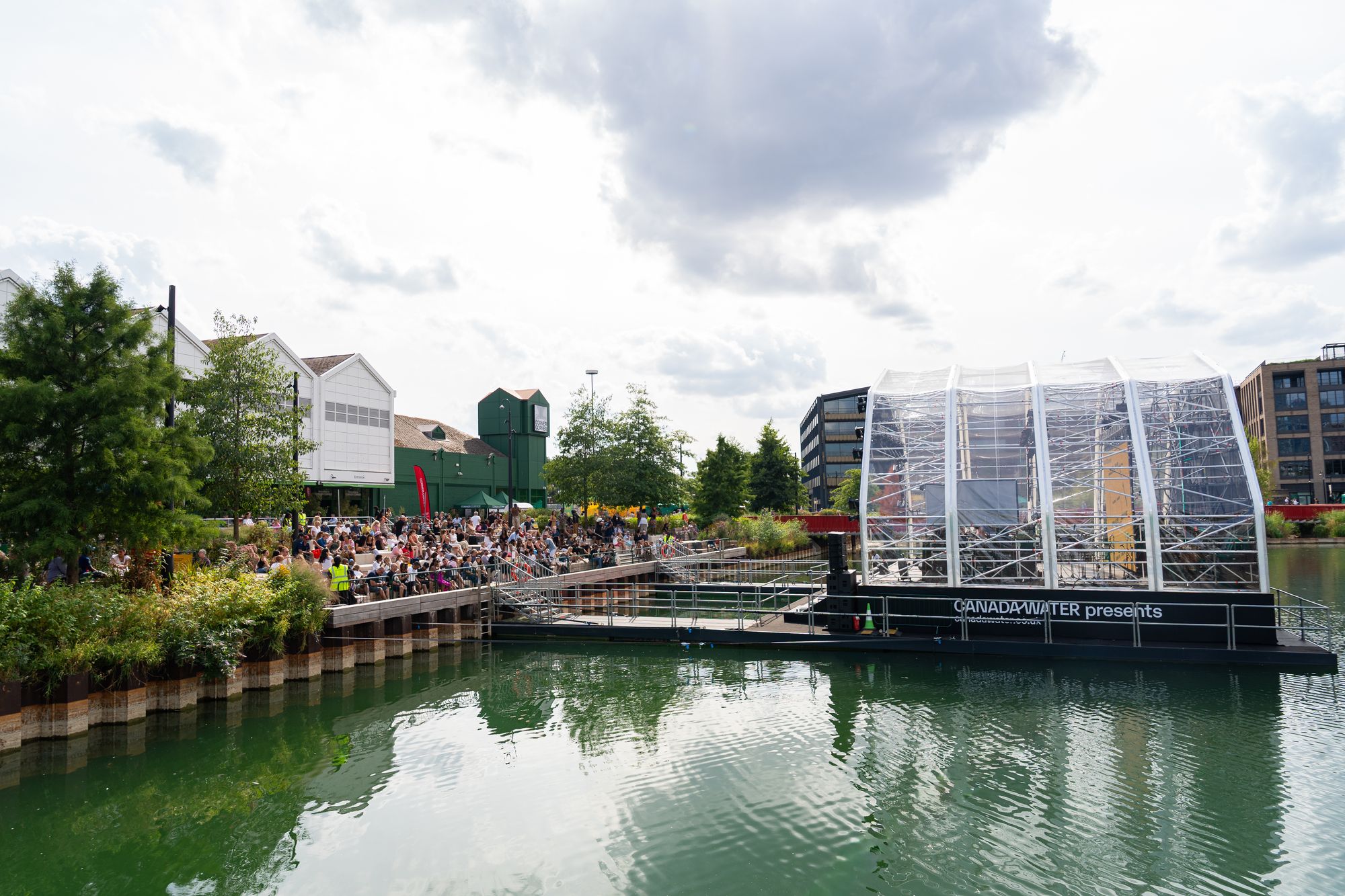 A wide view over Canada Dock with the floating stage and crowds on the far dockside during Round the Dock.