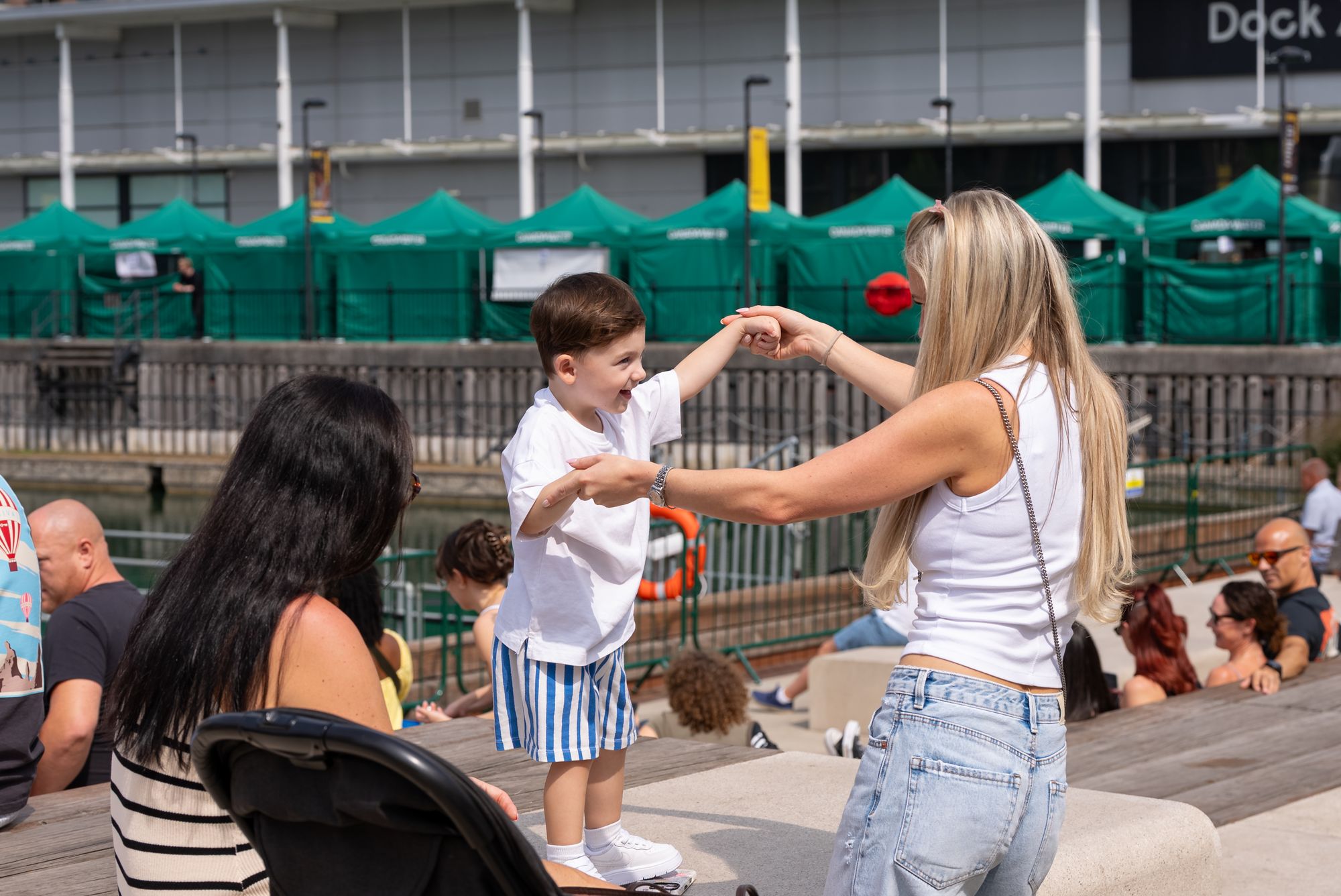 A young child dancing with family on the dockside at the Round the Dock festival.