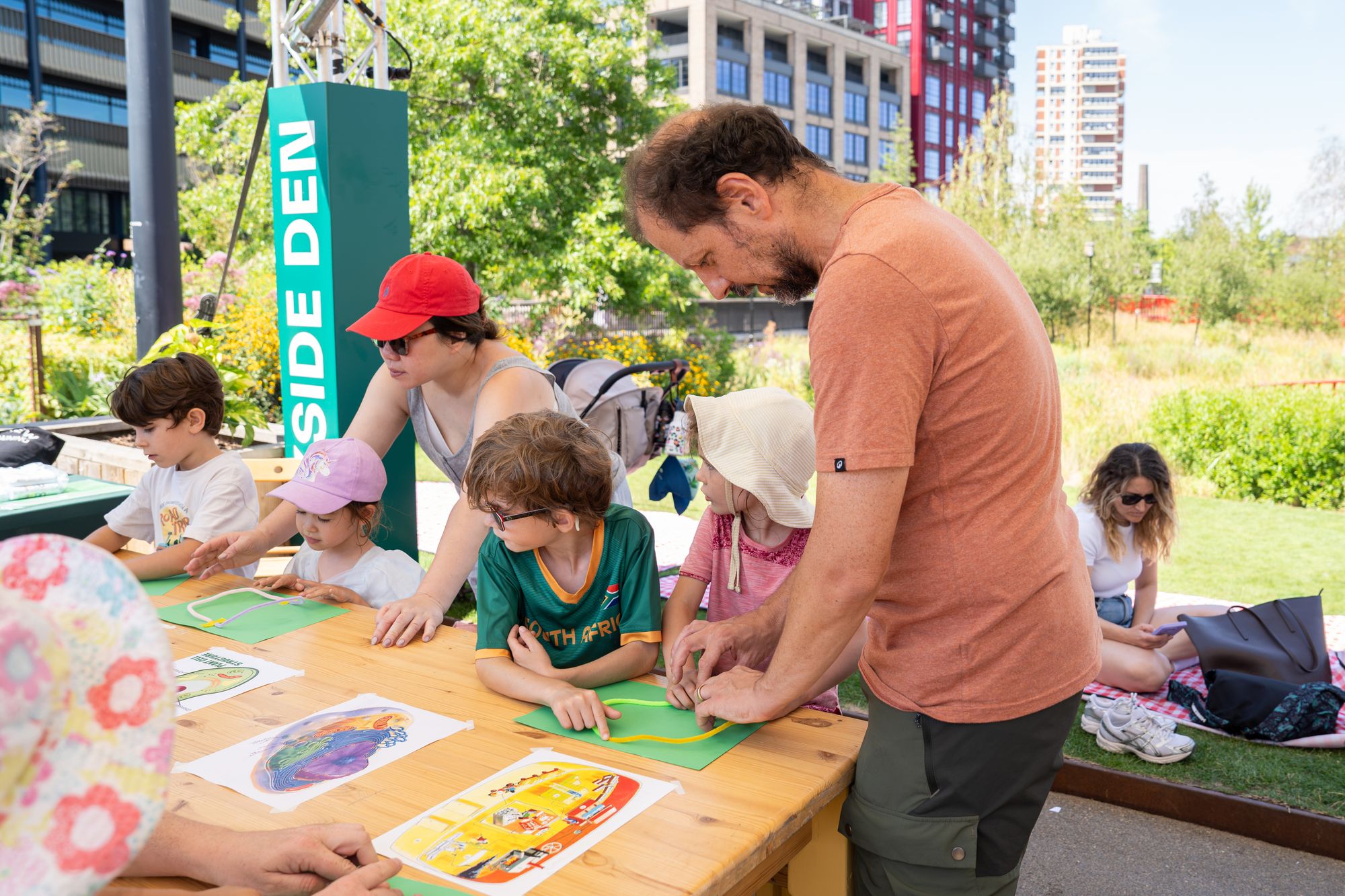 A parent and children crafting together under the Dockside Den sign at Canada Water.