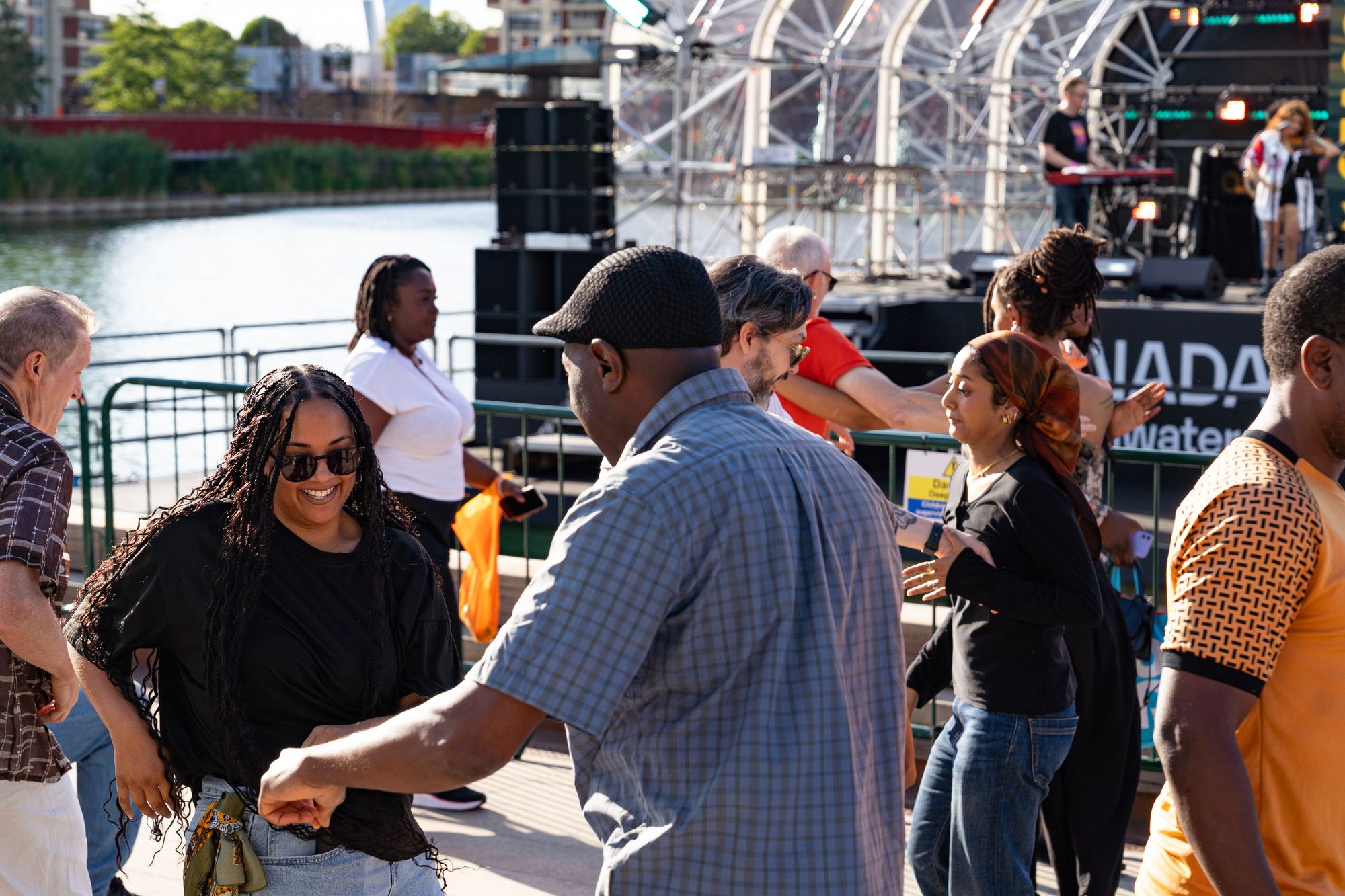 Couples dancing salsa on the dockside in front of the floating stage at Round the Dock, Canada Water, London SE16.