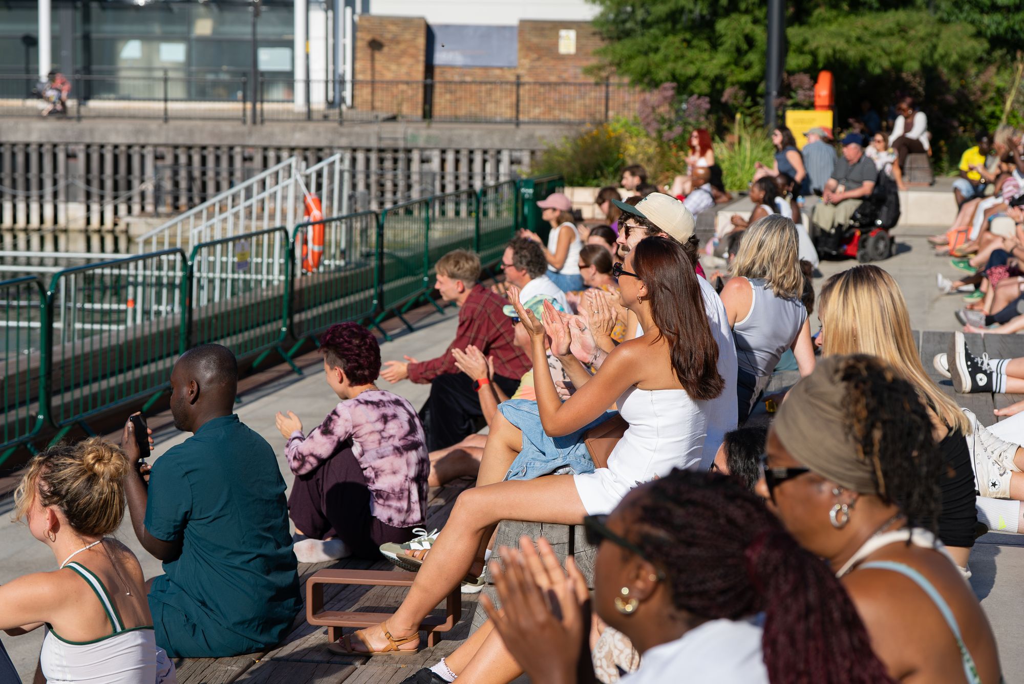 The Spit Night crowd gathered along the dockside in the evening sun at Canada Water, London.