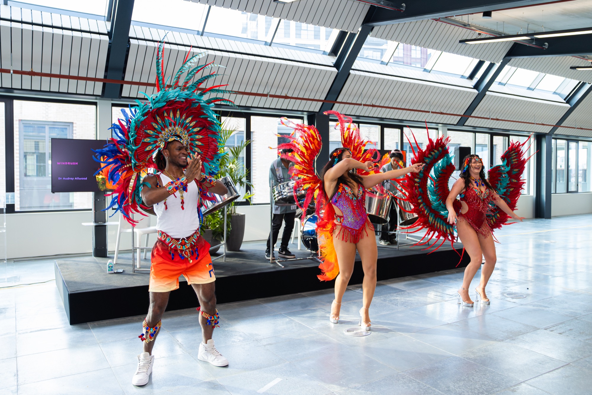 Carnival dancers in feathered costumes perform at the Windrush celebration in the Dock Shed, Canada Water, London.