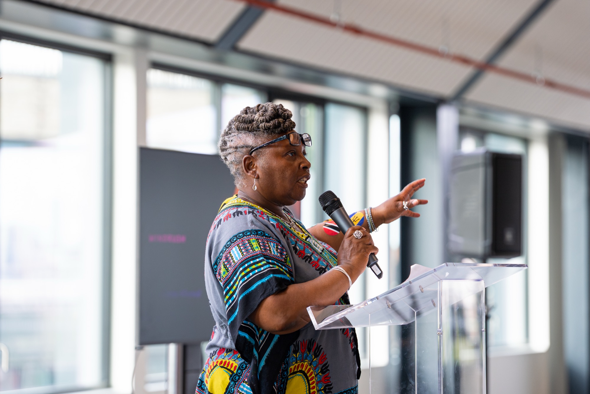 Dr Audrey Allwood speaking at the Windrush celebration at Canada Water — corporate event photography in London.