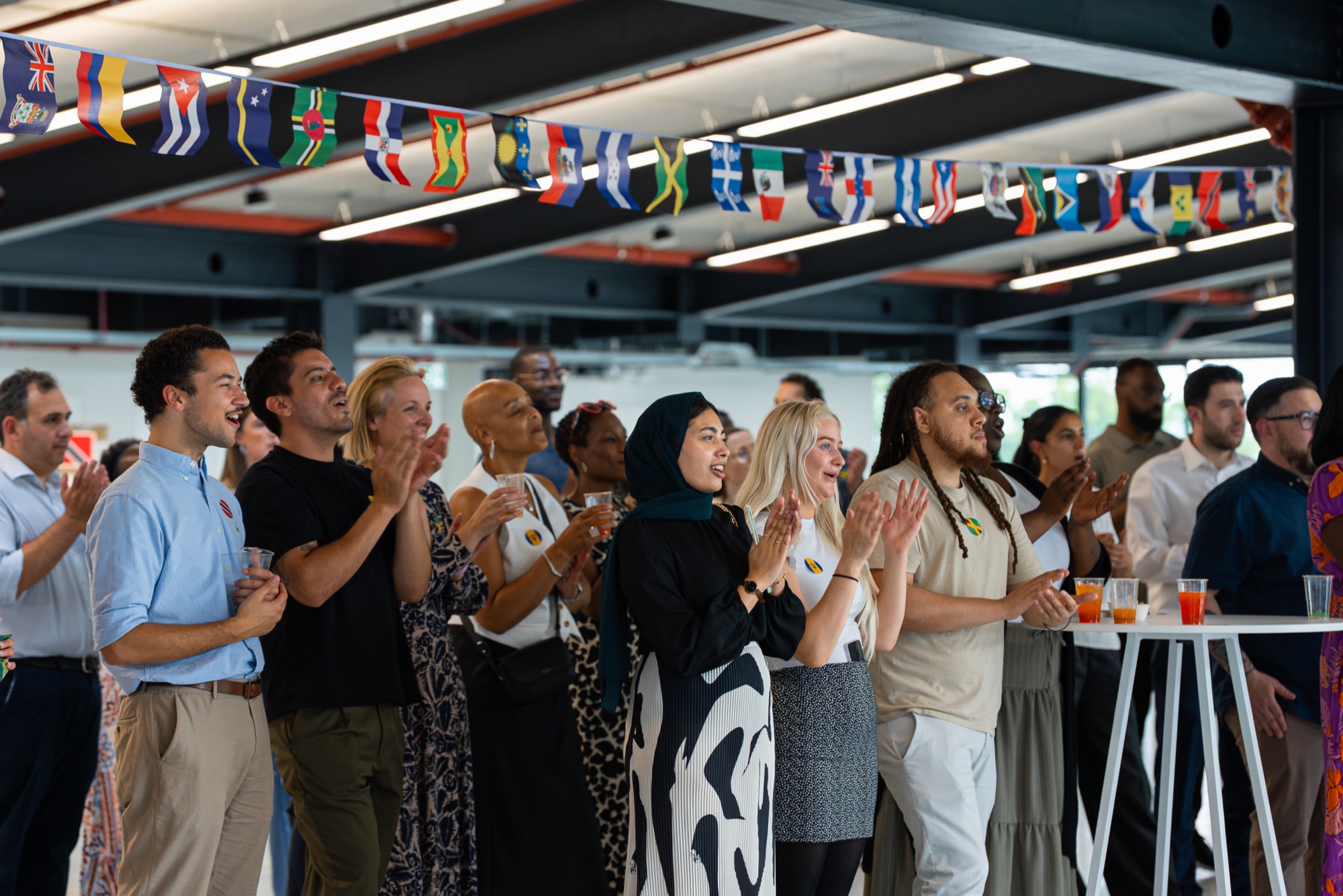Guests applaud the speeches beneath Caribbean flags at the Windrush celebration, Canada Water.