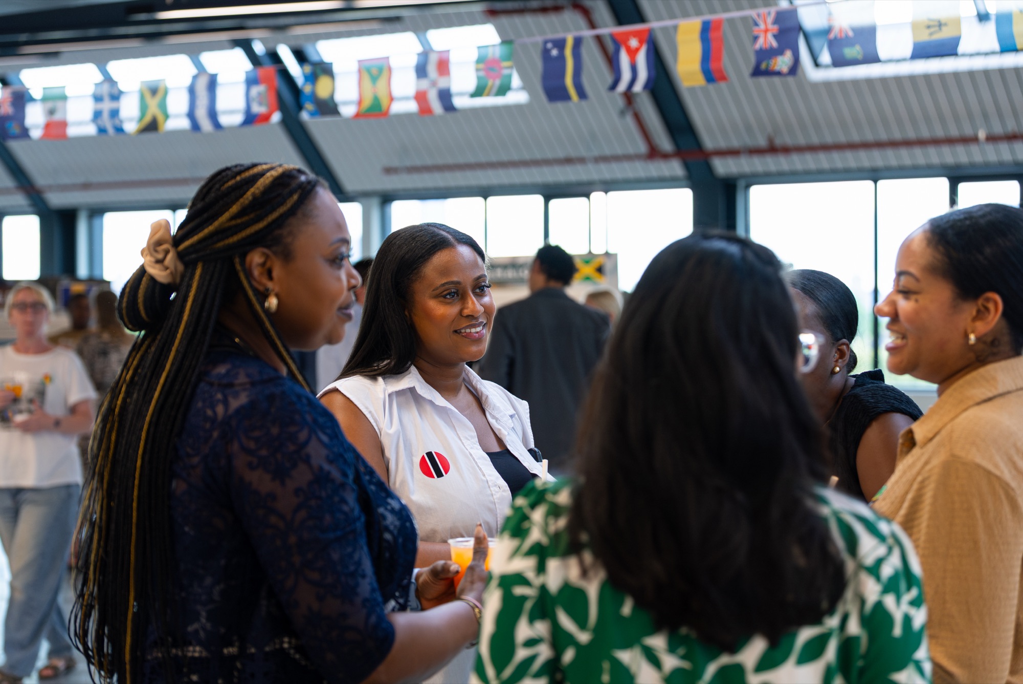 Guests in conversation beneath Caribbean flag bunting at the Windrush celebration, Canada Water.