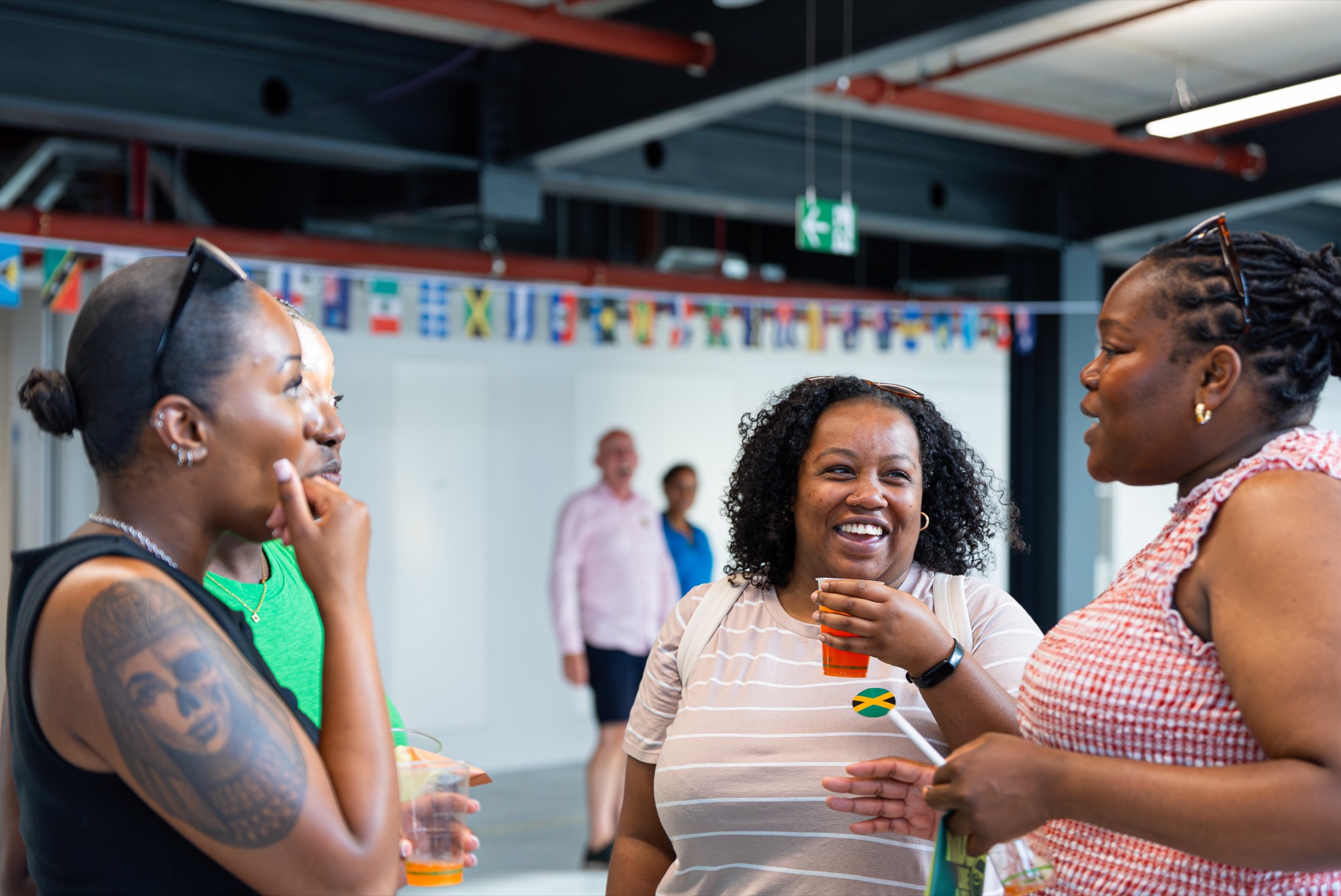 Three guests sharing a laugh at the REACH Windrush celebration in London.