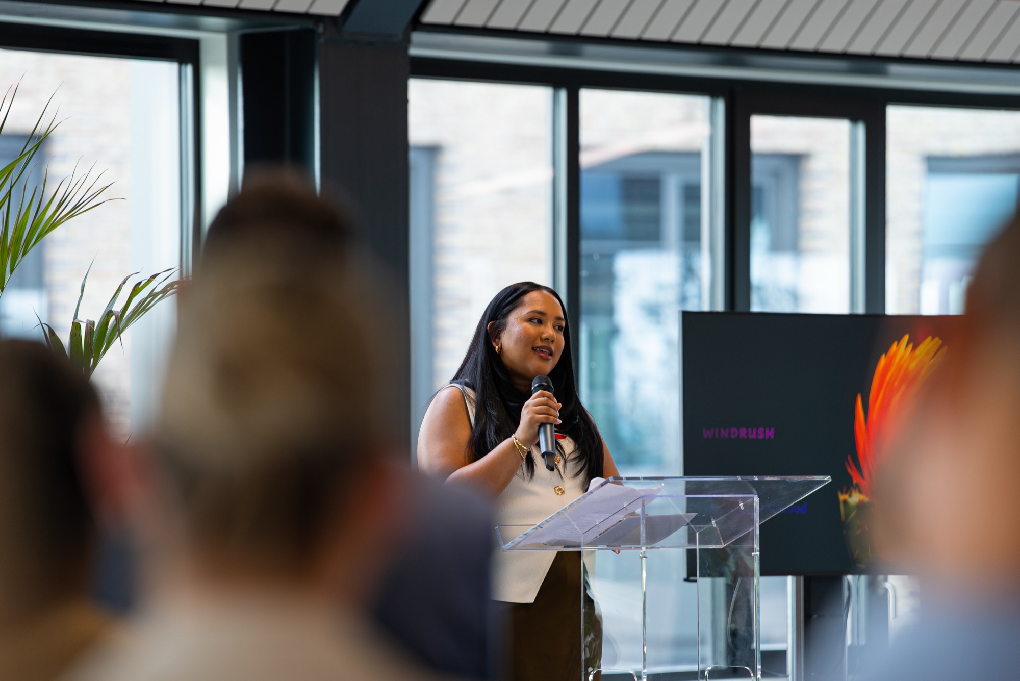 A host welcomes guests from the lectern at the REACH Windrush celebration, in partnership with CBRE and JLL.