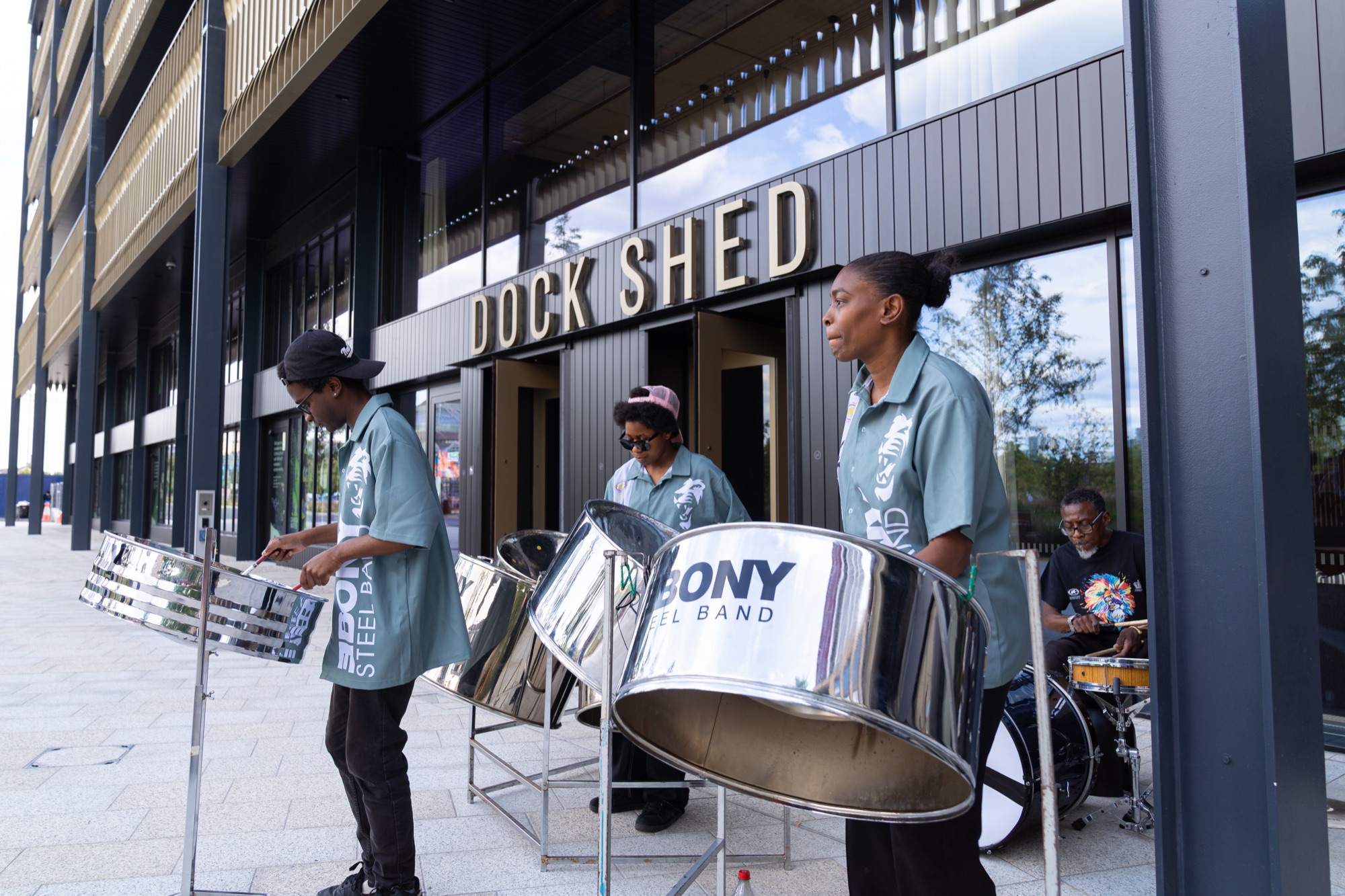 A steelpan band plays outside the Dock Shed at Canada Water during the Windrush celebration hosted by REACH.