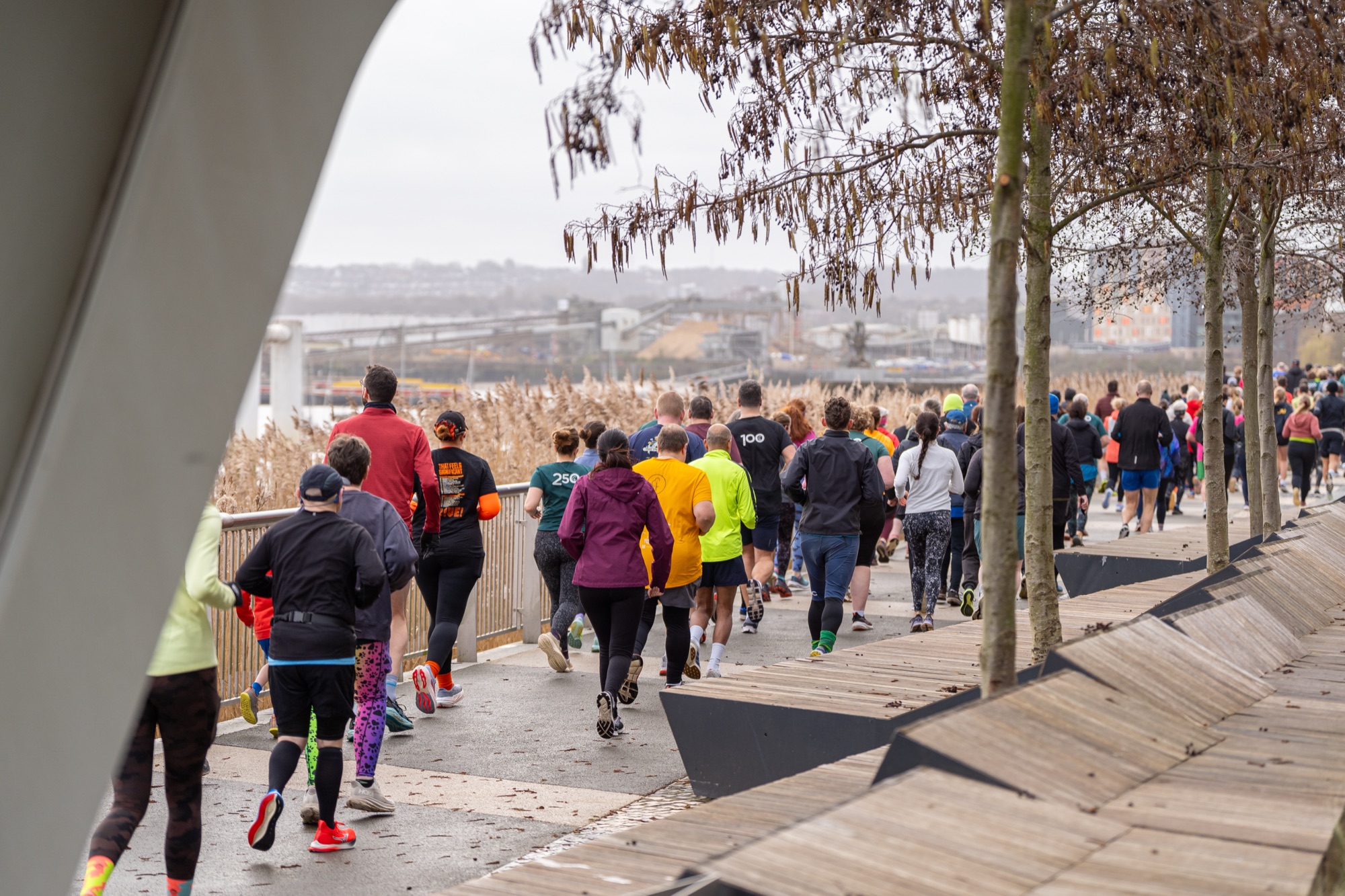 Runners moving along The Tide's elevated boardwalk with open views across the Thames — the riverside setting central to the parkrun's identity.
