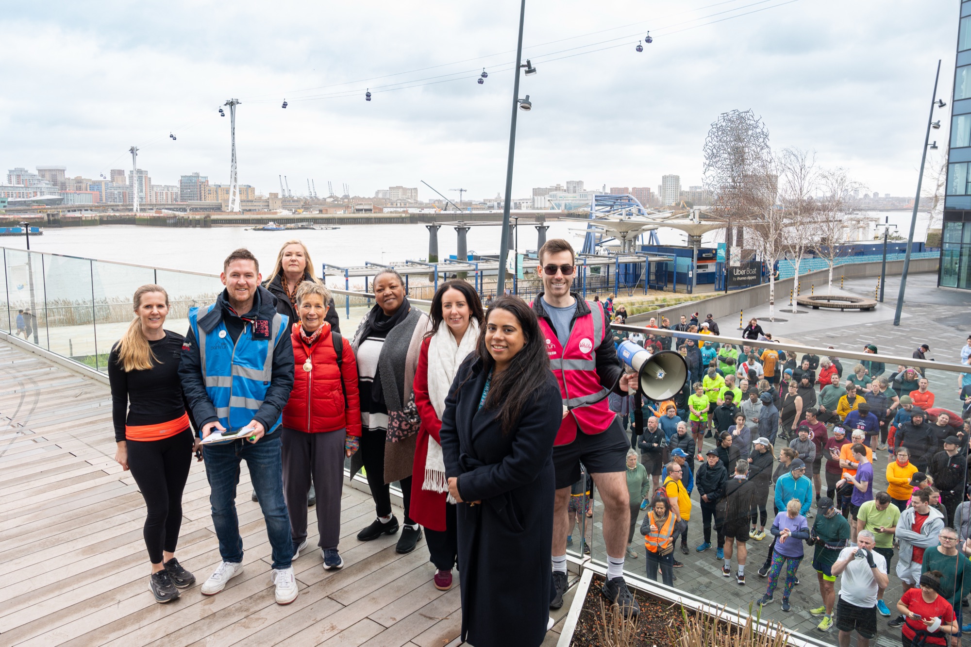 Knight Dragon's executive team and local councillors at The Tide photocall — cable cars, the O2, and the Thames providing the backdrop with runners below.