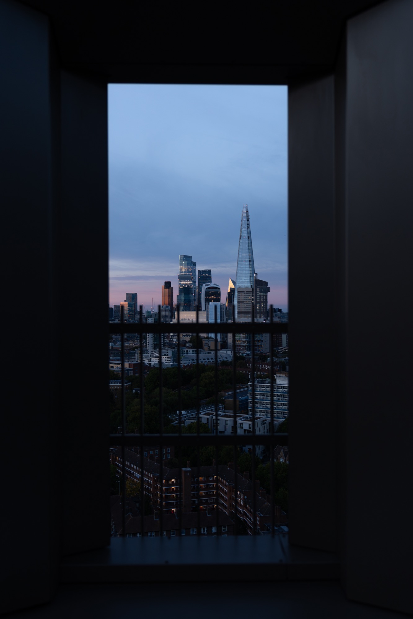 The City of London skyline at dusk, framed by a terrace doorway at Arbour Heights, Elephant Park.