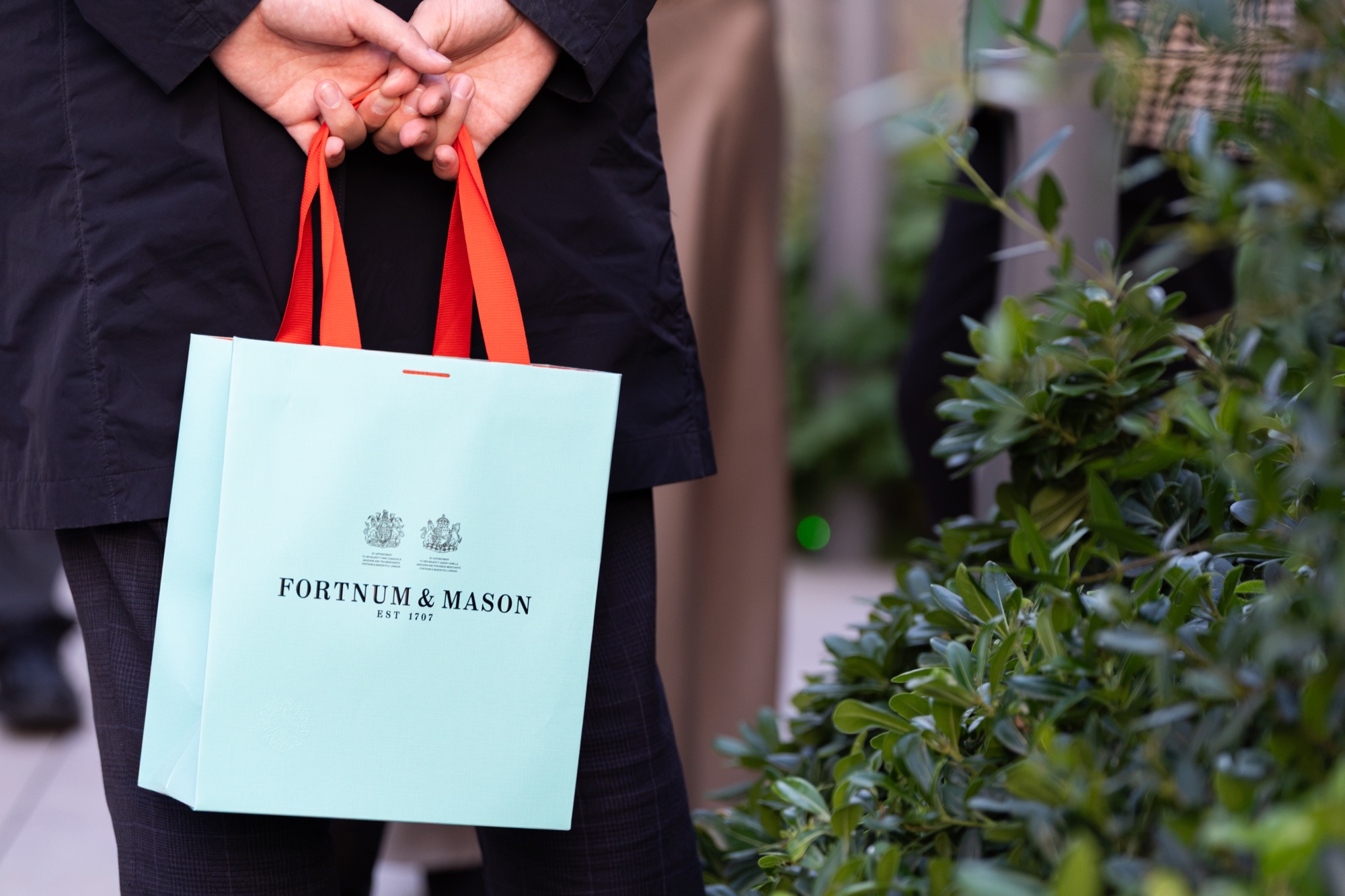 A guest holds a Fortnum & Mason gift bag on the terrace at the Arbour Heights launch, The Wilderly.