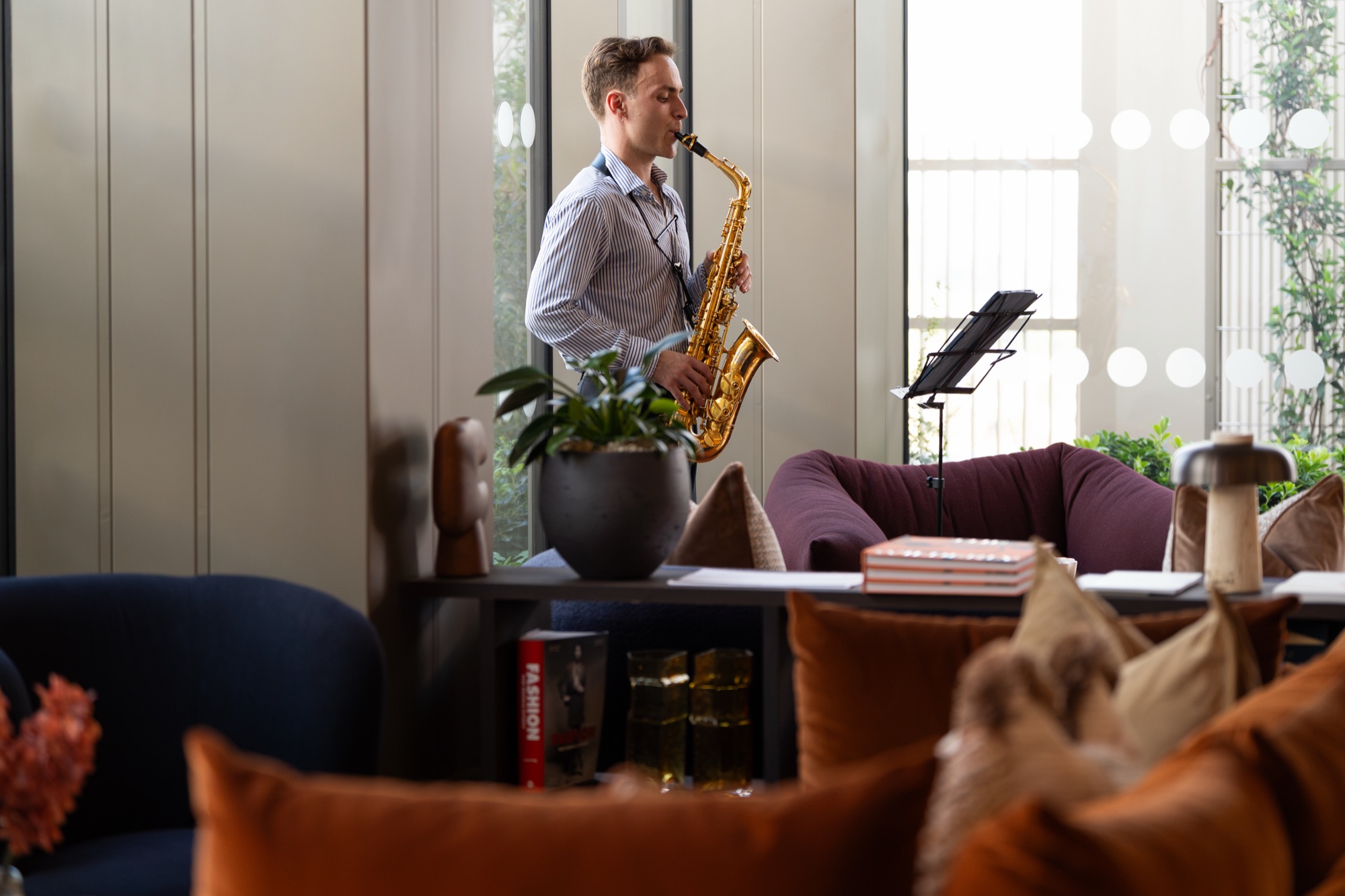 A saxophonist plays in the styled residents' lounge at Arbour Heights — interior photography for Lendlease.