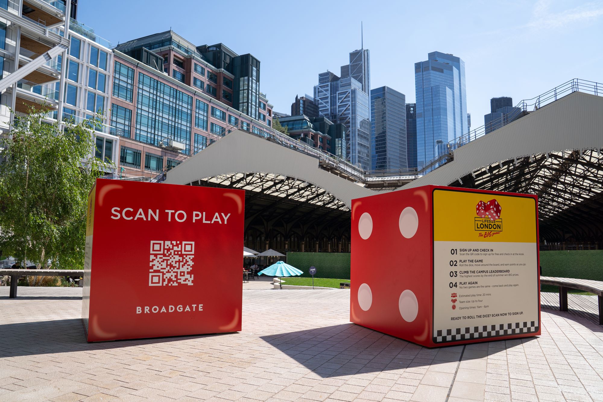 Giant dice and the Scan to Play cube in Exchange Square, Broadgate, with the City of London skyline behind.