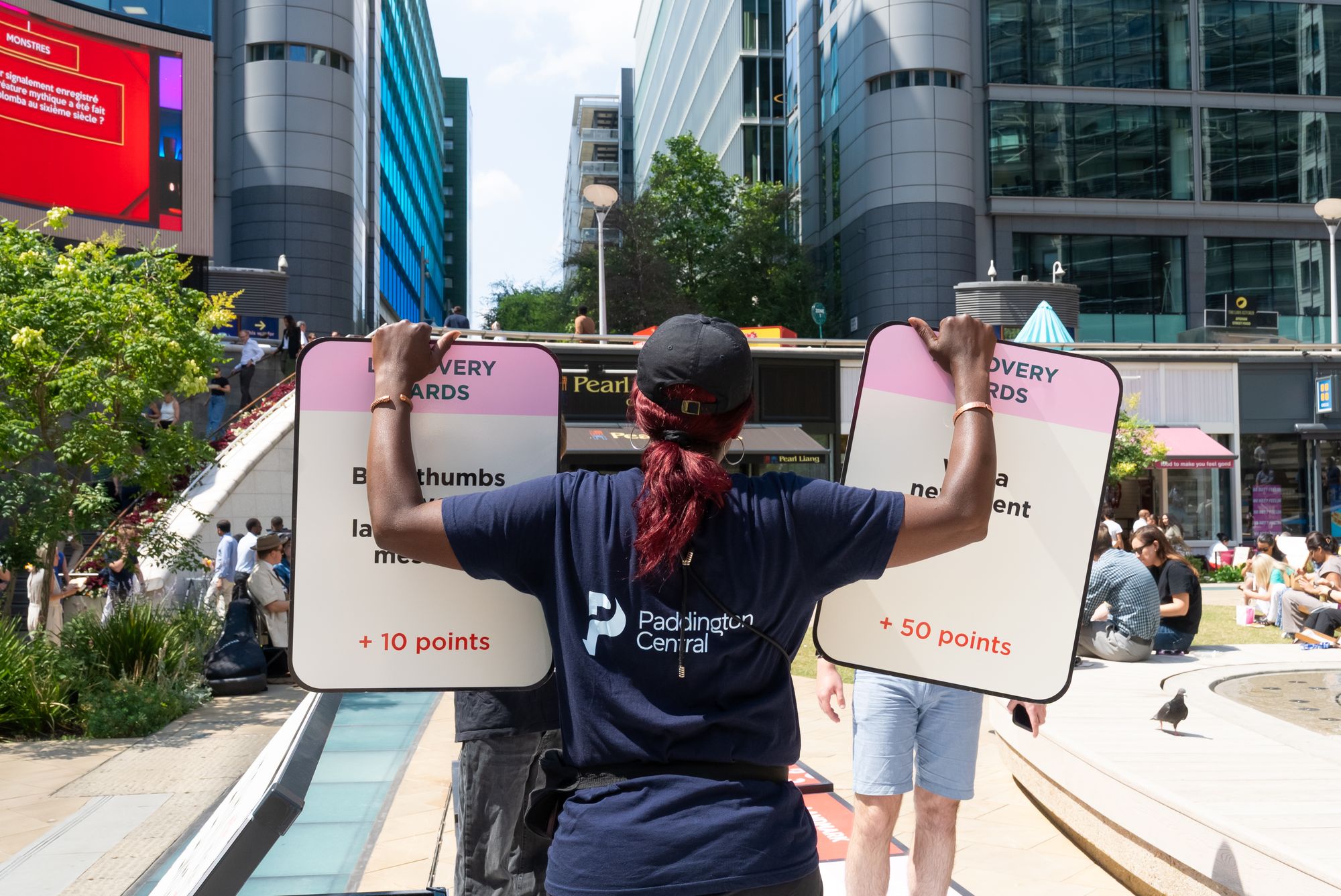 A game host holding up Discovery Cards for players at Paddington Central — event photography for British Land.