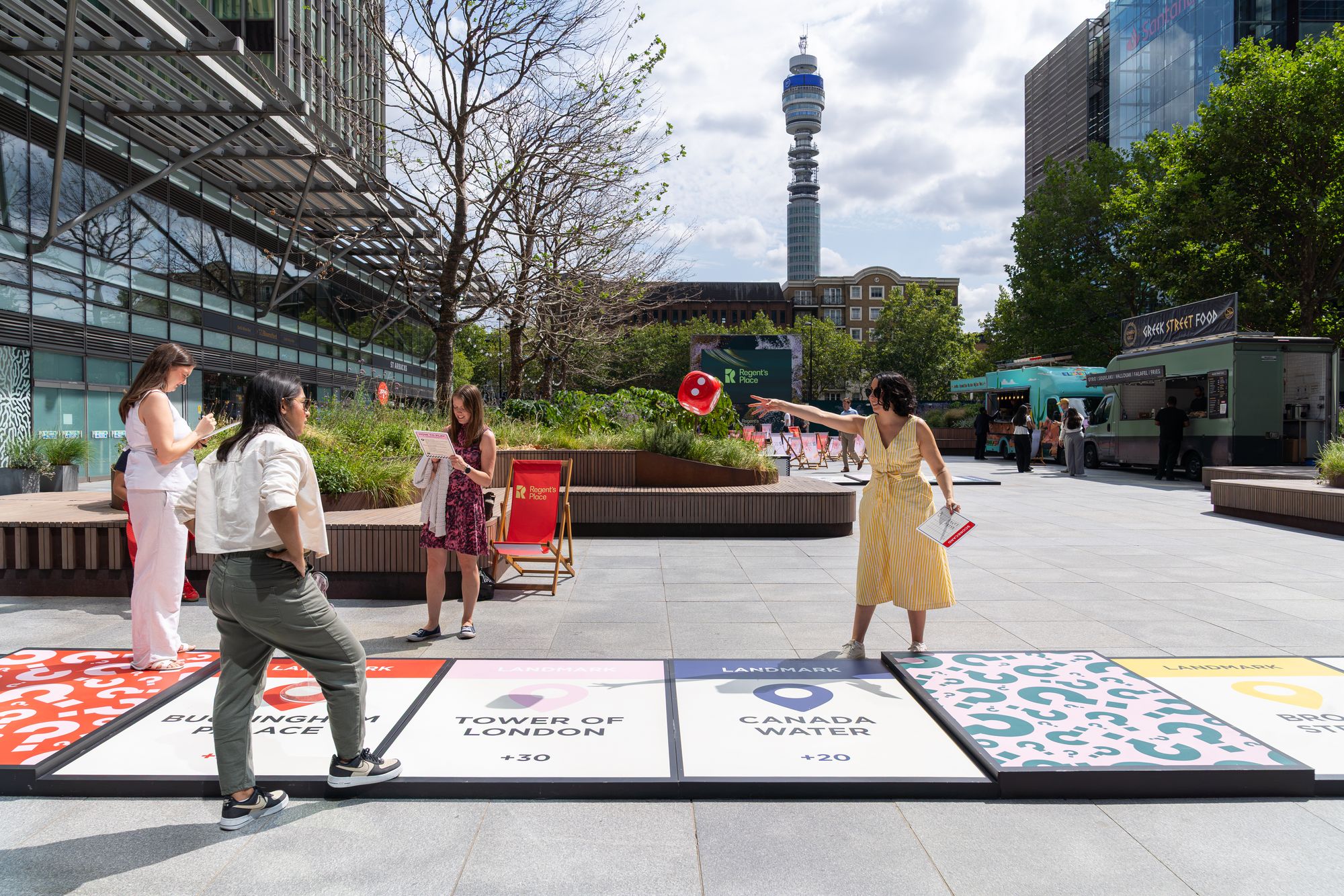 A giant dice mid-air as players take their turn on the Lifesize London board at Regent's Place, with the BT Tower behind.